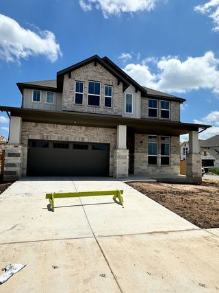 A beautiful stone facade home with a spacious driveway in Homestead at Old Settlers Park by Tri Pointe Homes (Round Rock, TX).
