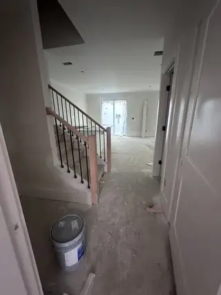 A spacious entryway leading to a staircase with elegant railing, showcasing construction progress in a modern home.