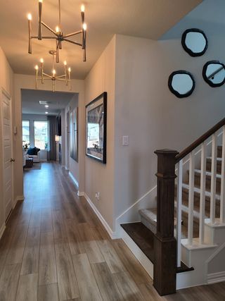 A contemporary hallway with sleek wood flooring, modern chandeliers, and elegant staircase detailing.
