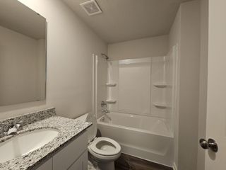A modern bathroom featuring a sleek granite countertop, a white vanity, and a pristine bathtub for a cozy, functional space.