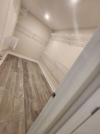 Model Home A spacious walk-in closet with ample shelving and hardwood flooring.