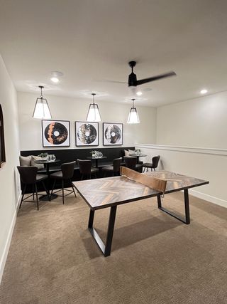 Model Home A cozy game room with a stylish ping pong table, modern lighting, and artistic wall decor for entertaining guests.