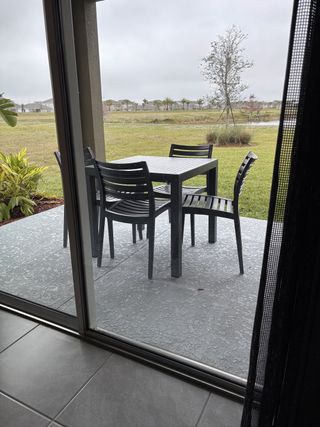 A cozy patio with modern black table and chairs overlooking a grassy landscape and pond.