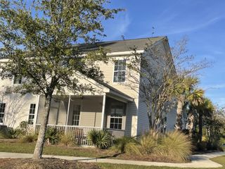 Charming two-story home with a cozy porch and lush landscaping in High Point at Foxbank by Dream Finders Homes (Moncks Corner, SC).
