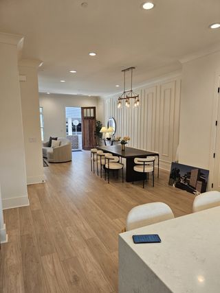 A beautifully designed open-concept dining space with elegant wall paneling, warm wood floors, and a statement chandelier.