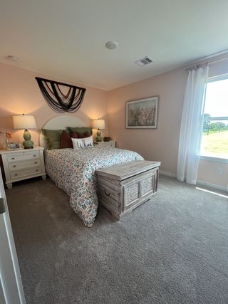 A cozy bedroom featuring soft pink walls, a floral bedspread, and elegant decor with ample natural light filtering through windows.