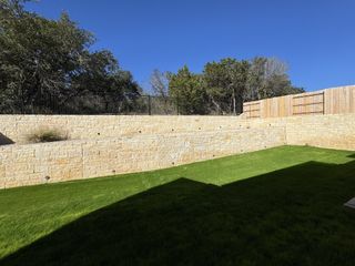 Model Home A spacious backyard with tiered stone retaining walls, offering privacy and natural beauty.
