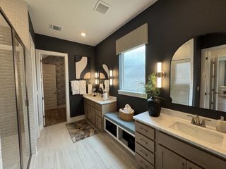 A modern bathroom with dark walls, elegant dual vanities, stylish lighting, and chic decor accents.