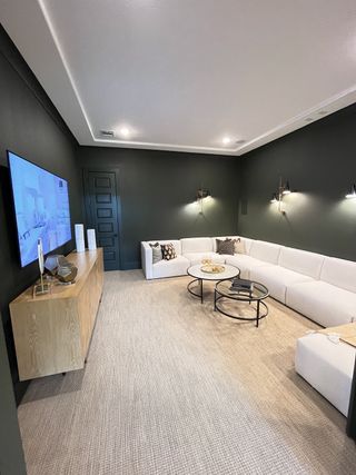 A cozy media room with a plush white sectional, sleek black walls, and a stylish wooden console for a contemporary feel.
