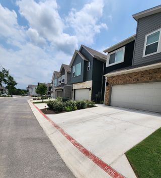 A stylish row of contemporary townhomes in Village on Cooper Lane by David Weekley Homes in Austin, TX, featuring sleek architecture and well-maintained landscaping.