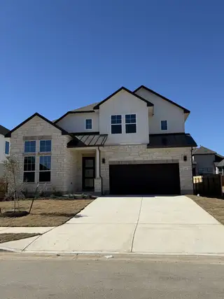 Street view A modern stone and siding home with a spacious driveway in Santa Rita Ranch by GFO Home (Liberty Hill, TX).