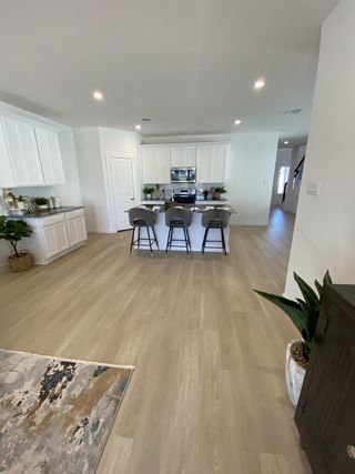 A bright kitchen with white cabinets, a sleek island, and wood flooring. Cozy and modern design with ample lighting.