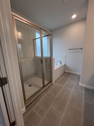 A stylish master bathroom featuring a large glass-enclosed shower, soaking tub, and elegant tile flooring.