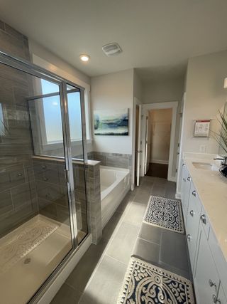 A modern bathroom with a glass shower, soaking tub, dual vanity, and elegant gray tile flooring.
