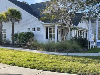Street view A charming white home with lush landscaping in High Point at Foxbank by Dream Finders Homes (Moncks Corner, SC).