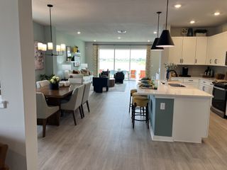 An open-concept kitchen and dining area with modern lighting, stylish decor, and a view of serene waters.