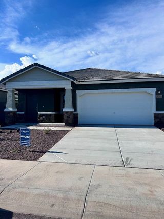 A modern gray home with a white garage and stone accents in Canyon Views by Starlight Homes, Litchfield Park, AZ.