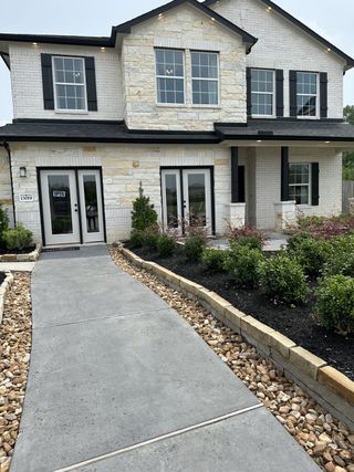 A charming white brick home with elegant shutters and landscaping in Caney Mills by CastleRock Communities (Conroe, TX).
