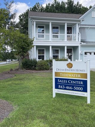 A charming light blue two-story home with a welcoming porch in Tidewater at Lakes of Cane Bay by Dream Finders Homes (Summerville, SC).