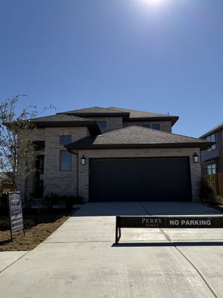 A modern brick home with dark garage in Santa Rita Ranch by Perry Homes (Liberty Hill, TX).