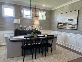 Elegant dining room with textured walls, modern chandelier, and stylish artwork. Neutral tones and sleek furniture create warmth.