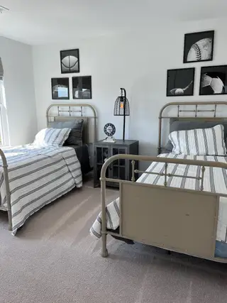 A cozy bedroom featuring twin metal beds, striped bedding, and sports-themed wall art for a modern touch.