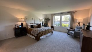 A spacious bedroom with elegant bedding, cozy seating area, and large windows for natural light.