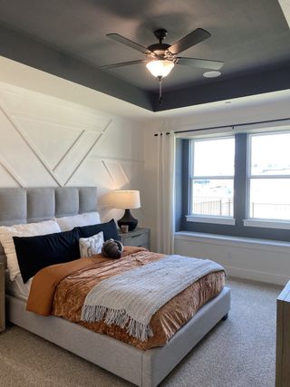 A cozy bedroom featuring a plush upholstered bed, chic accent wall, and large windows for natural light.