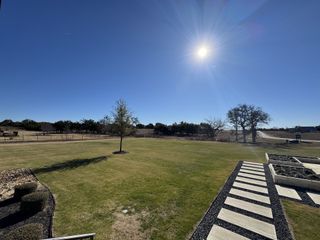 Model Home A sprawling green backyard with a modern stone pathway, perfect for relaxation in North Haven by GFO Home (Liberty Hill, TX).