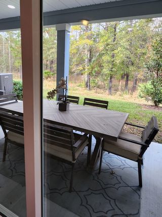 Model Home Cozy patio dining area with wooden table, cushioned chairs, and serene forest views, perfect for relaxed outdoor gatherings.