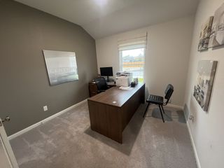 A cozy office with a wooden desk, chair, and wall decor, featuring neutral tones and natural light.