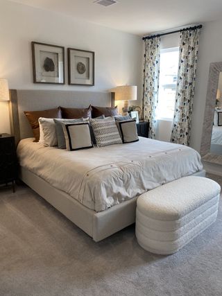A cozy bedroom featuring an upholstered bed with elegant pillows, patterned curtains, and soft lighting.