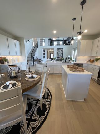 An elegant open-concept kitchen with modern lighting, white cabinetry, and a cozy dining area with a round table.