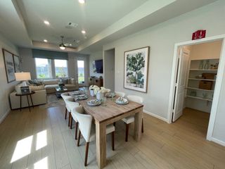 A bright, open living and dining space with wood floors, modern decor, and large windows for plenty of natural light.