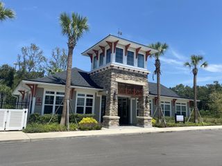 Community Amenities A charming community center at Wilford Oaks by Dream Finders Homes, featuring stone accents and palm trees in Orange Park, FL.