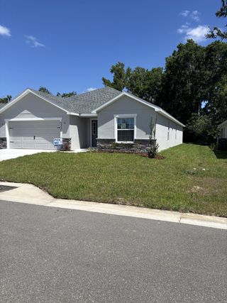 Street view A charming modern home with a manicured lawn in Bennah Oaks by Highland Homes of Florida (Belleview, FL).