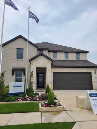 Street view A modern stone facade home with landscaped flowers in Southridge - Spring Series by Meritage Homes (McKinney, TX).