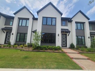 A modern white brick townhouse with sleek black trim in Viridian by Cadence Homes (Arlington, TX).