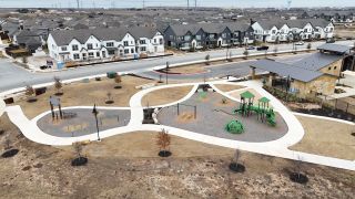 Aerial view of modern homes and a vibrant community park in Emory Crossing 40s by Taylor Morrison (Hutto, TX).
