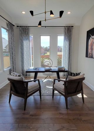 A bright, modern office with elegant lighting, wood flooring, and large windows for natural light.