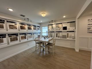 A bright design selection room with various material samples neatly displayed on the walls and a consultation table in the center.
