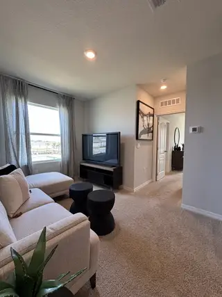 A spacious loft with neutral tones and contemporary furniture in Osceola Village Townhomes by D.R. Horton (Kissimmee, FL).