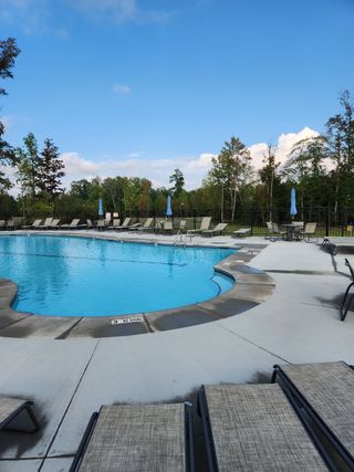 Community Amenities A pristine community pool with ample lounge chairs under a clear blue sky. Pearces Landing Single Family Homes by Ryan Homes (Zebulon, NC).