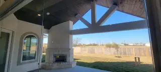 Model Home A spacious patio with a stone fireplace and vaulted ceiling offers a serene view of the backyard.