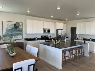 A modern kitchen with sleek white cabinets, a spacious island, and elegant dining area featuring contemporary artwork.