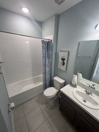 Model Home A modern bathroom with a ceramic-tiled bathtub, sleek vanity, and bright lighting.