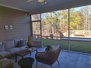 A serene screened porch with cozy seating, outdoor views, and a wooden deck, perfect for relaxation.