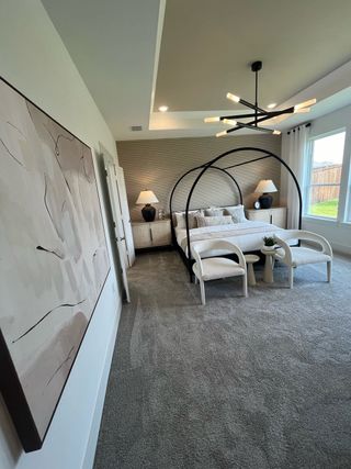 A modern bedroom with a sleek canopy bed, textured wall, abstract art, and contemporary lighting.