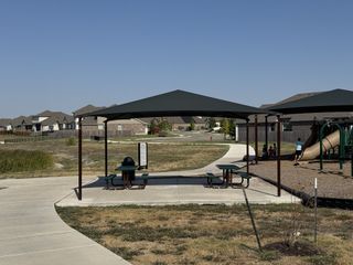 A scenic outdoor pavilion with picnic tables, perfect for gatherings and shaded relaxation in Blackhawk by GFO Home (Pflugerville, TX).