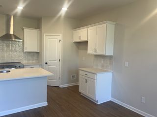 A bright kitchen with white shaker cabinets, quartz countertops, stainless steel appliances, and light wood flooring, offering a clean, modern aesthetic.